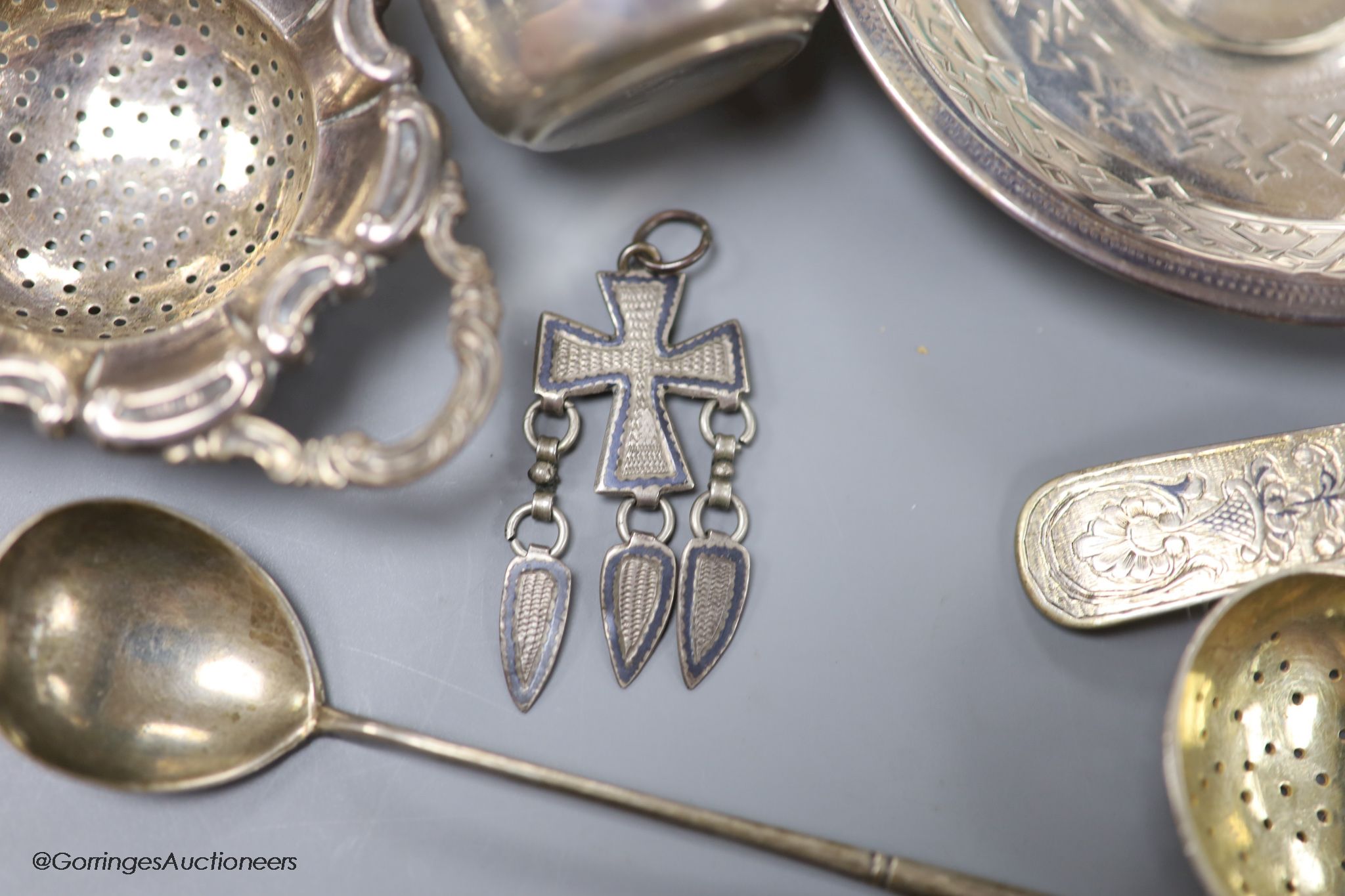 A late 19th century Russian engraved 84 zolotnik beaker, 1893, 63mm, a similar saucer, 1886, three assorted similar spoons, a white metal thimble and pendant and a German 835 tea strainer